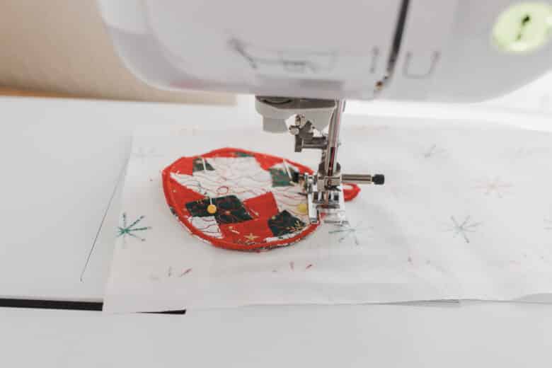 sew backing onto ornament by sewing around on the embroidery stitching