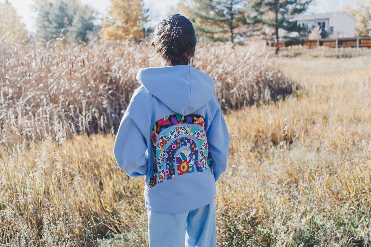 learn how to make a DIY rainbow sweatshirt. Add a fun rainbow fabric design to the back of of a sweatshirt with this fun sweatshirt sewing hack.